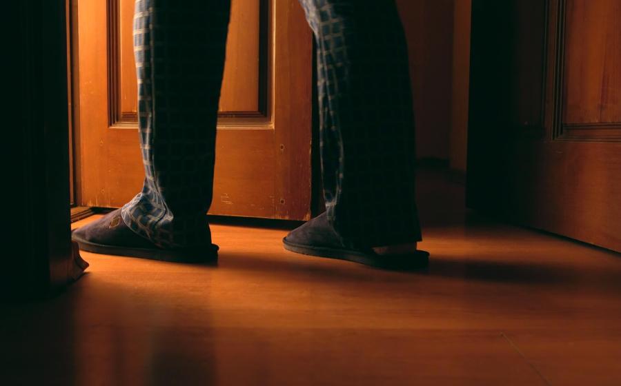 Man's legs and feet as he walks through door