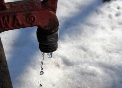 Red tap leaking water onto snow